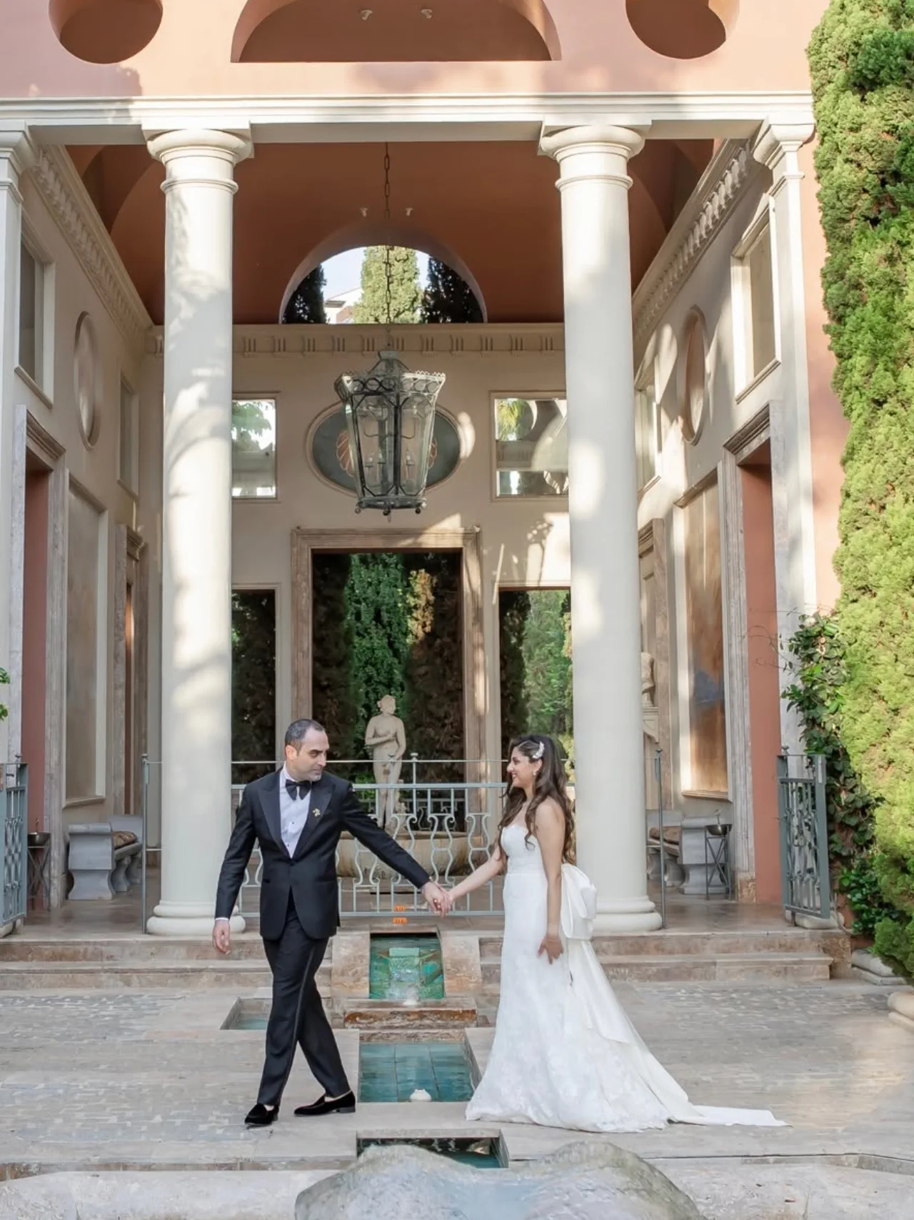 Shirin y Reza caminan de la mano bajo una columnata del Anantara Villa Padierna