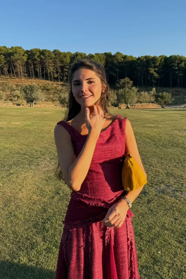 La madrina, hermana del novio, sonríe en el césped de Cortijo Curiel con un semirrecogido que deja caer mechones sobre la cara