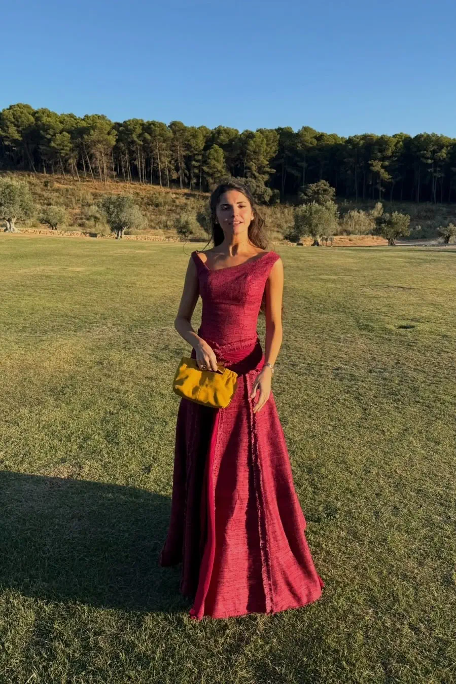 La madrina de cuerpo entero en la hora dorada, con un vestido granate casi frambuesa de Ángel Palazuelos