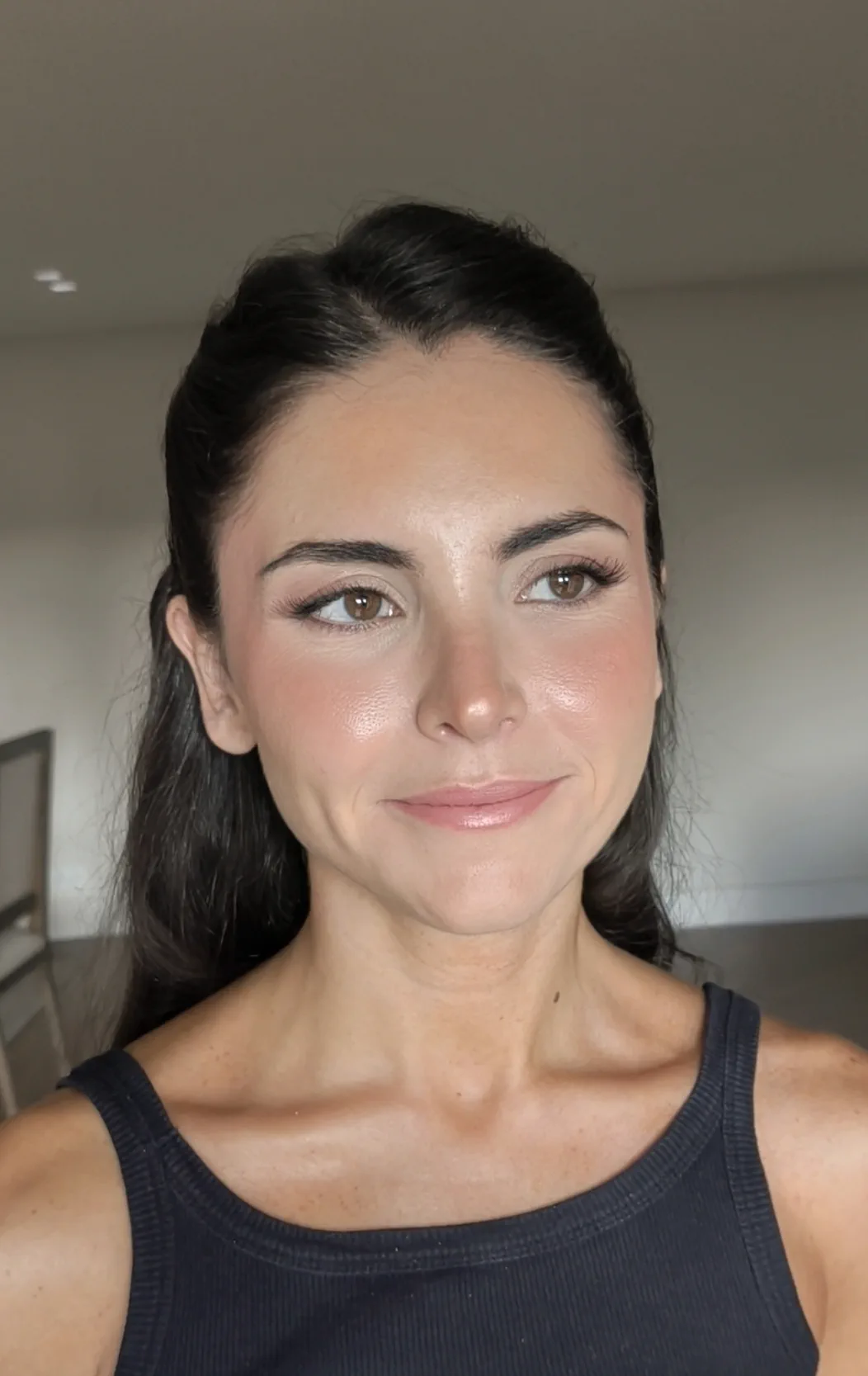 La madrina por la mañana, recién maquillada y peinada, con la piel luminosa, rubor suave y el pelo recogido hacia atrás