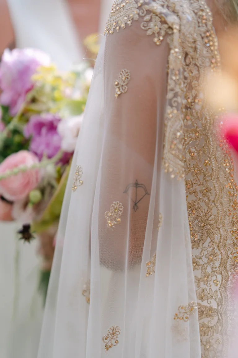 Detalle del bordado dorado de la capa pakistaní junto al ramo de colores