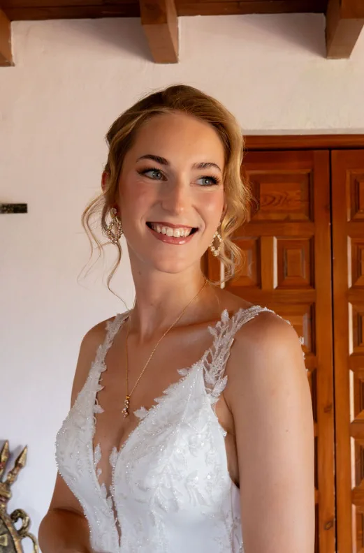 Novia sonriente con vestido de encaje y recogido con mechones sueltos en Fort Inglés, Mijas