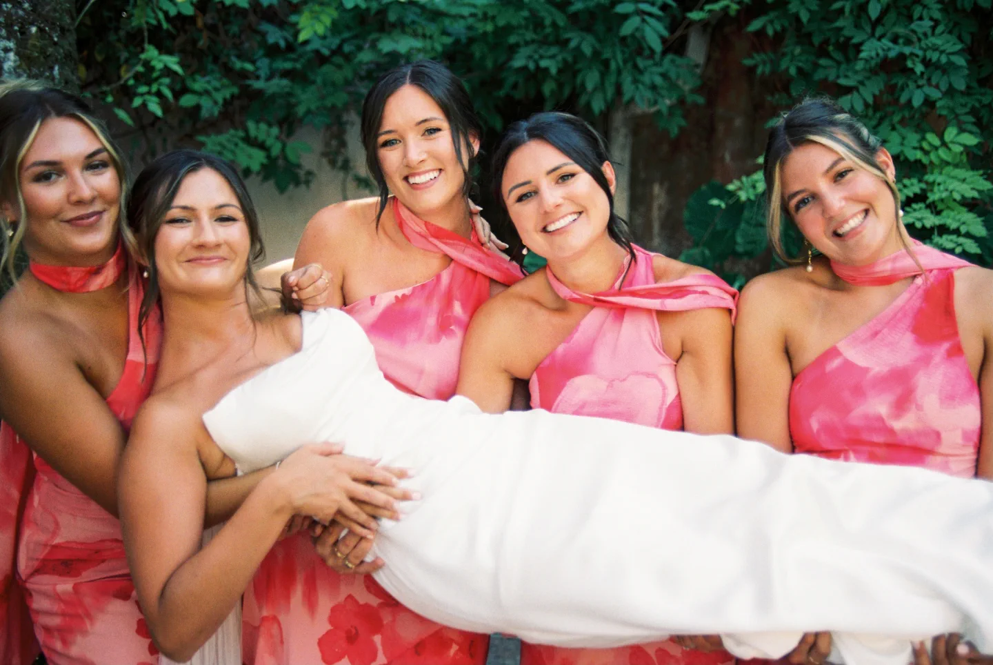 Las damas de honor levantan a la novia entre risas en el jardín de El Molino del Duque, Manilva