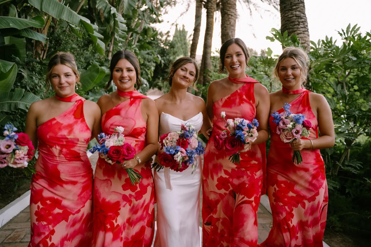 La novia y sus damas de honor, de vestidos rosas y con los ramos, en el jardín de El Molino del Duque