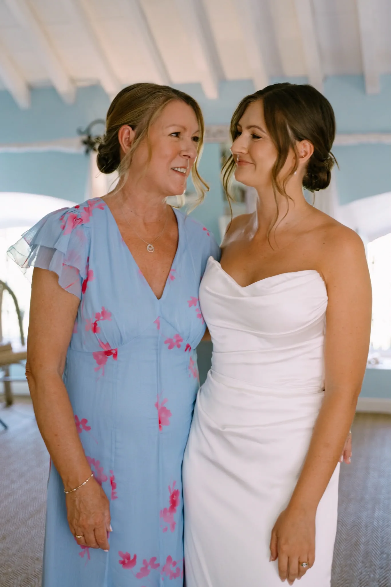 La novia, ya vestida, y su madre, de vestido azul, se miran
