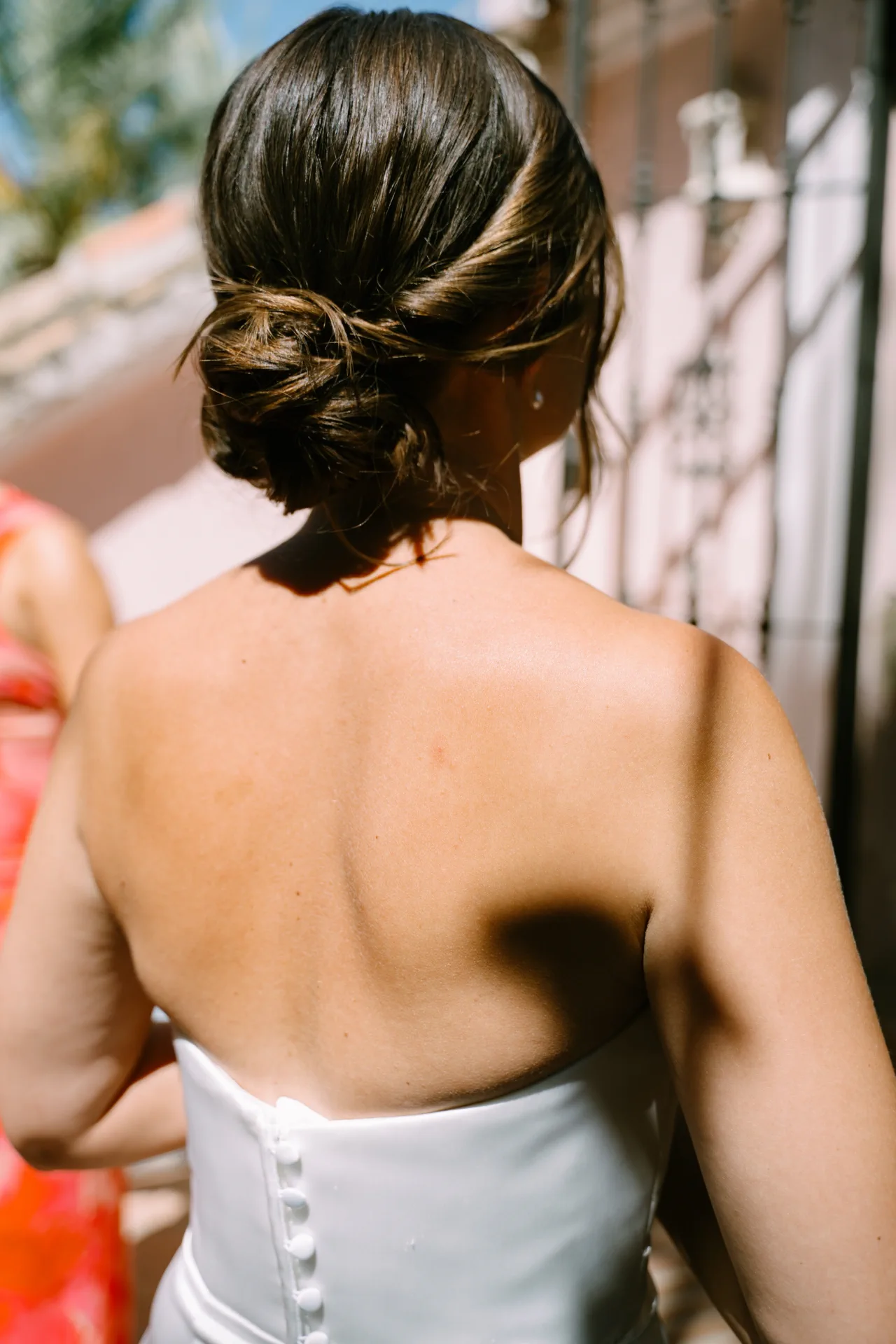 La novia, de espaldas junto a la ventana, con el recogido bajo y algún mechón suelto