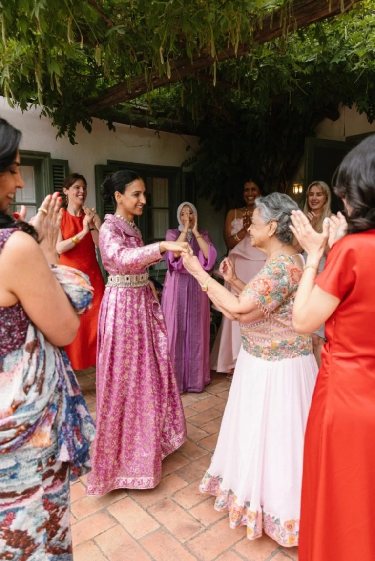 Mujeres de la familia de Hanadi, vestidas de rosa, fucsia y rojo, bailan y dan palmas en la terraza