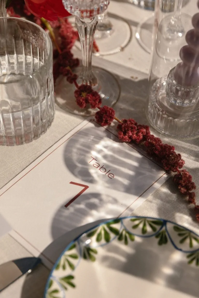 Guirnalda de flores rojas junto a la cristalería y el número de mesa