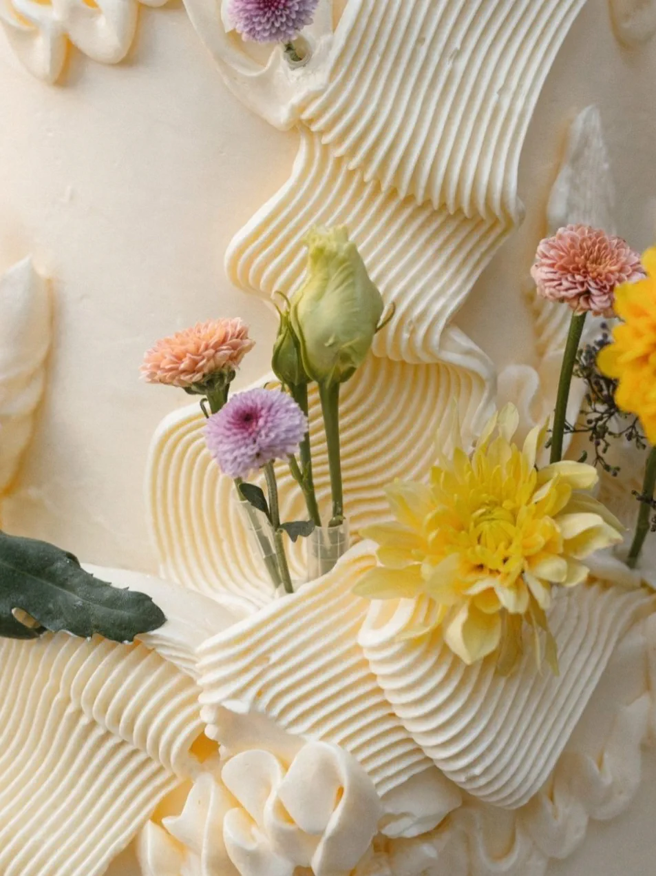 Detalle de la crema de la tarta, trabajada en pliegues, con flores amarillas y lilas