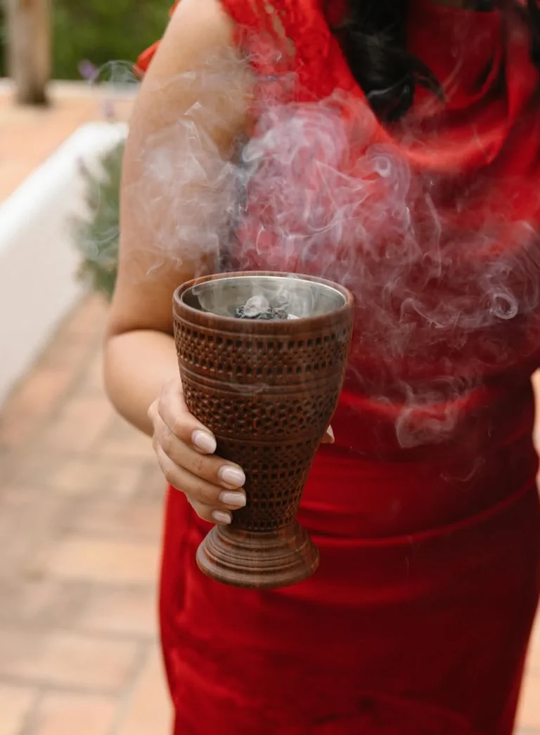 Un incensario de madera humea sobre un vestido rojo durante uno de los rituales de la boda