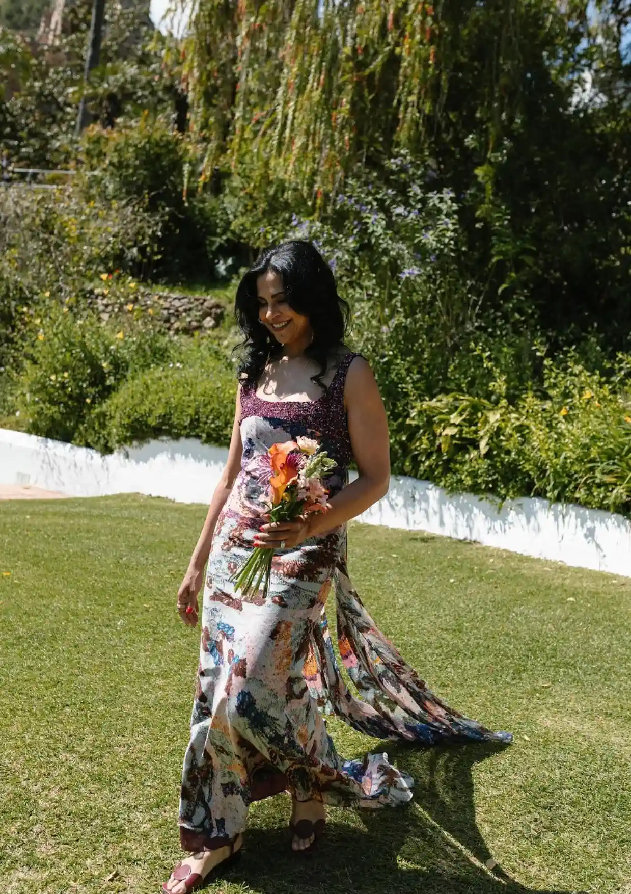 La madre de Hanadi, con ondas y un ramo de flores, camina por el césped