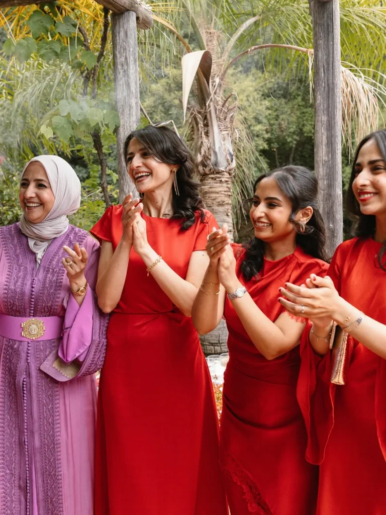 Amigas de la novia, con ondas y vestidos rojos, dan palmas en el jardín de Torre de Tramores, Benahavís