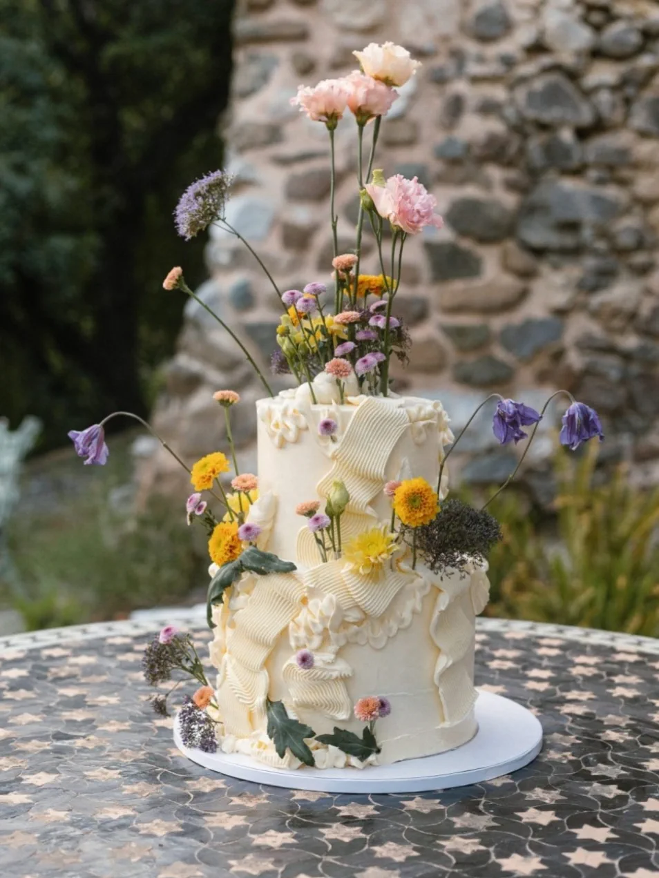 La tarta de boda, blanca y de varios pisos, con flores frescas de colores