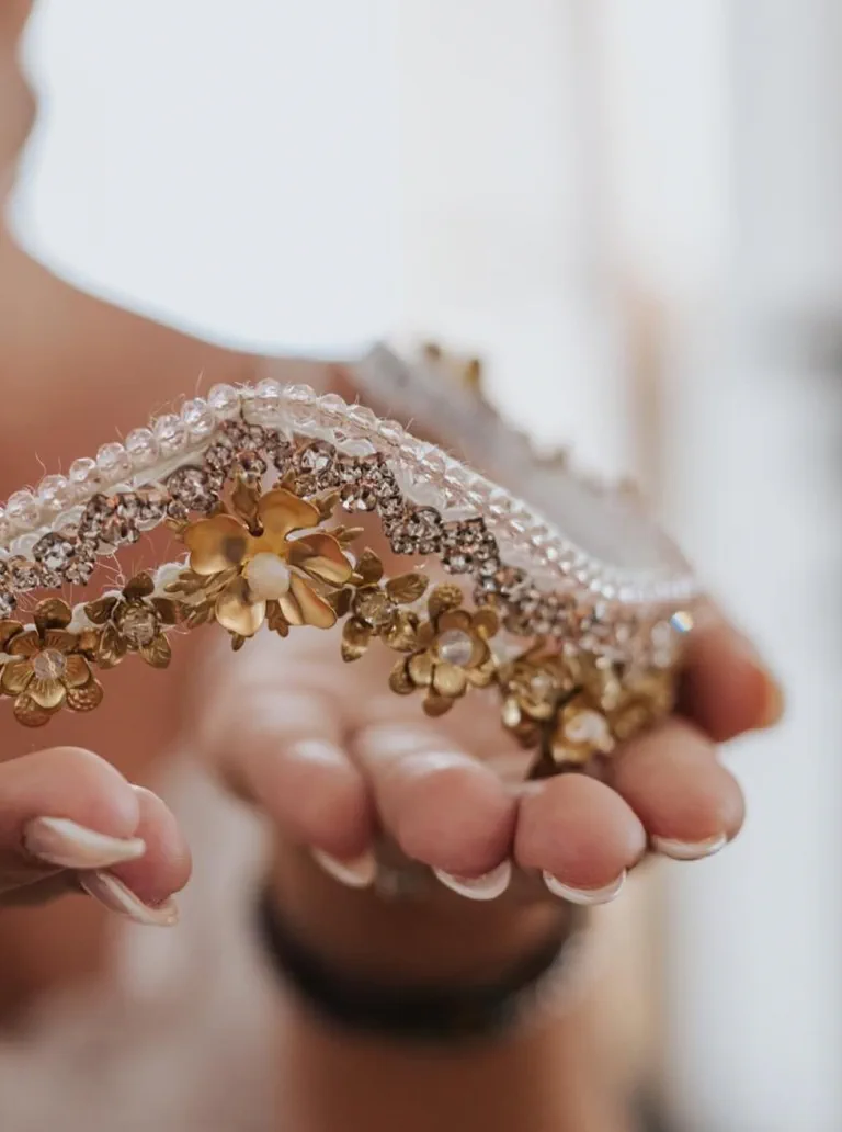 La novia sostiene su tiara dorada con pedrería