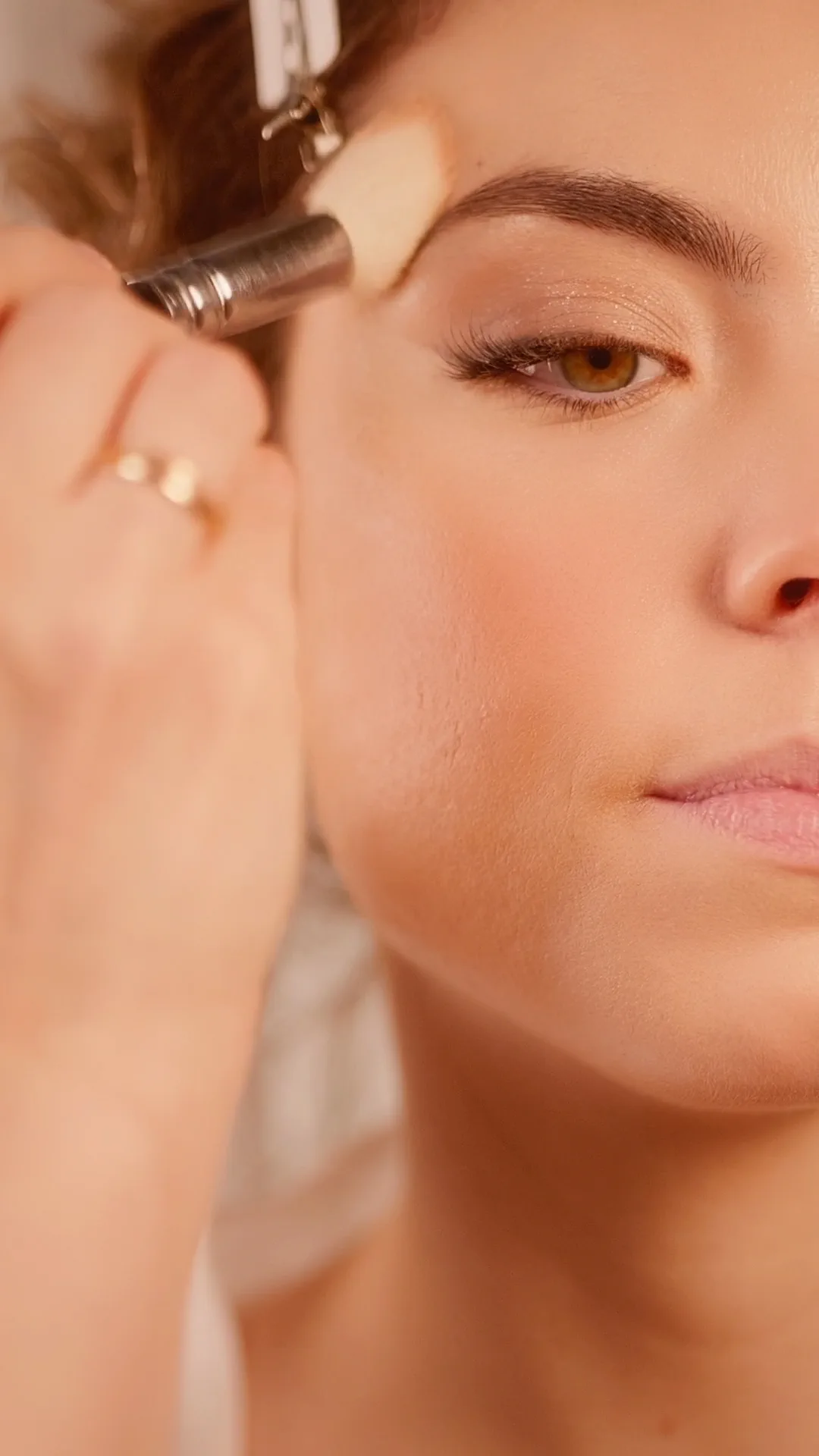 Una brocha trabaja la ceja de la modelo en un maquillaje de líneas minimalistas