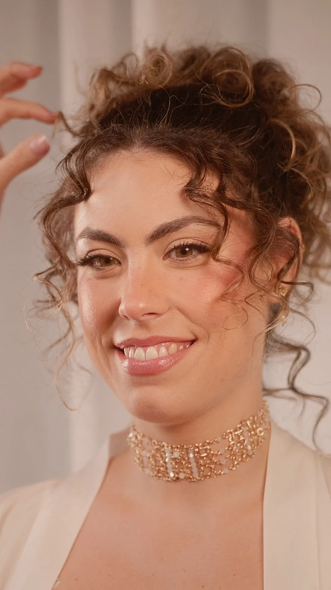 Recogido alto de estilo griego con el rizo natural y un choker dorado